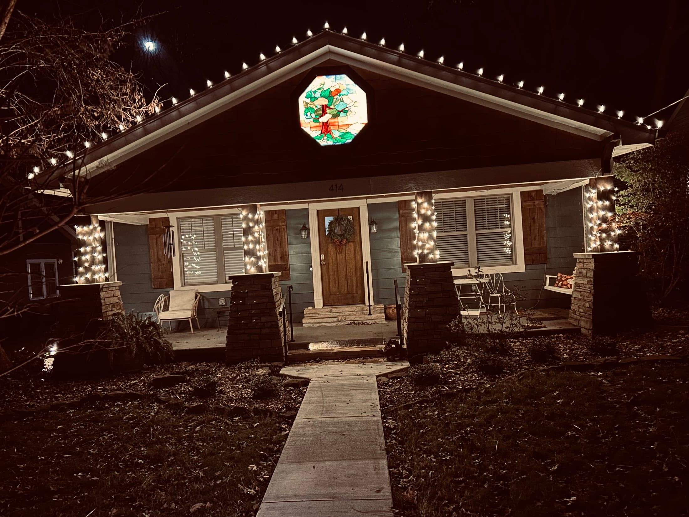 Warm-white roofline and column lighting on a cottage-style home