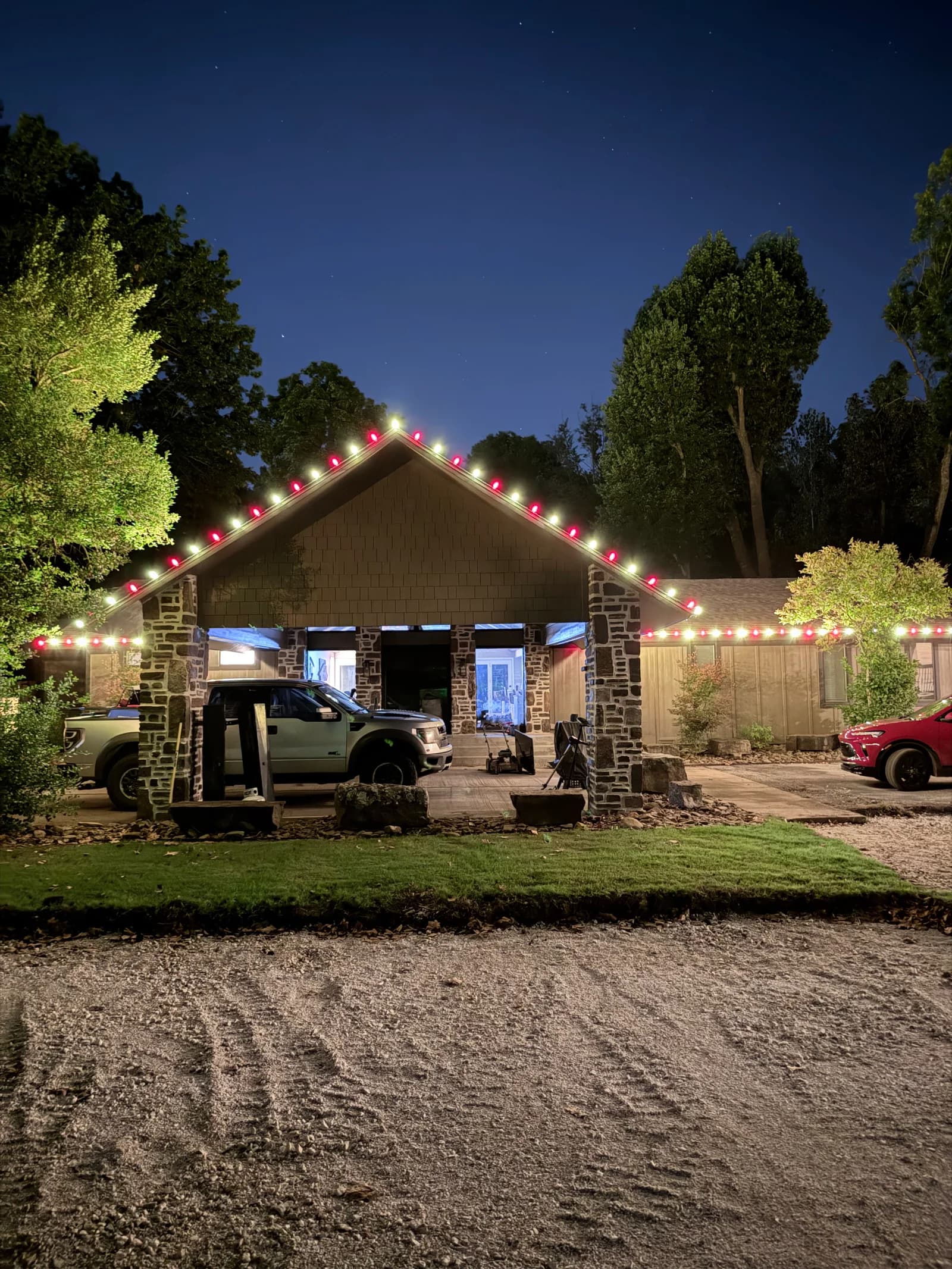 Alternating red and warm-white lights outline a steep gable and the adjoining roofline of a home at night